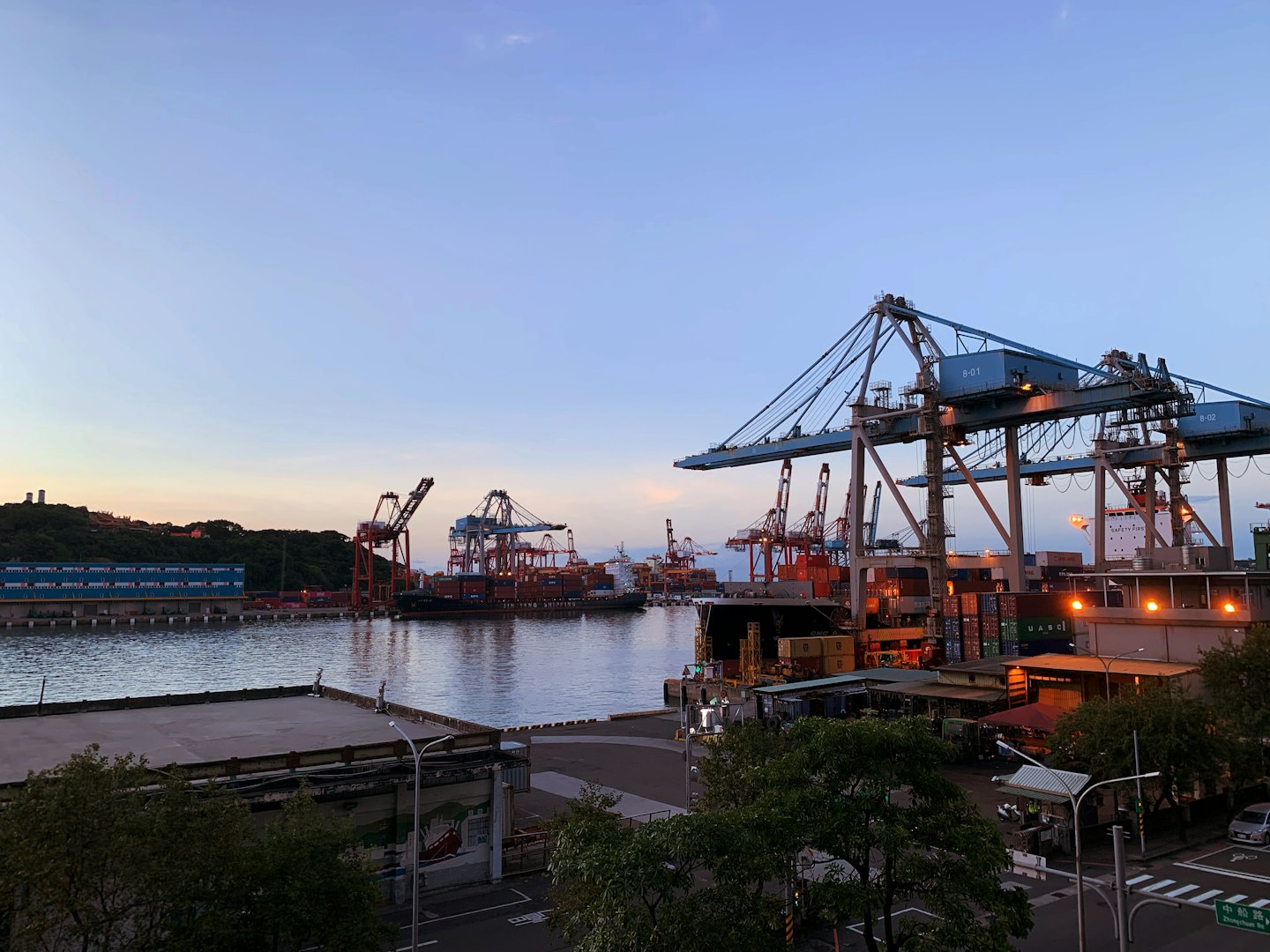 Gantry cranes load shipping containers onto ships at a busy port.