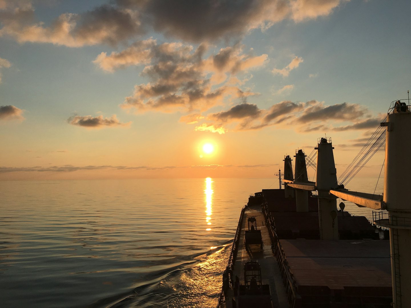 A large cargo ship sails across the calm ocean.